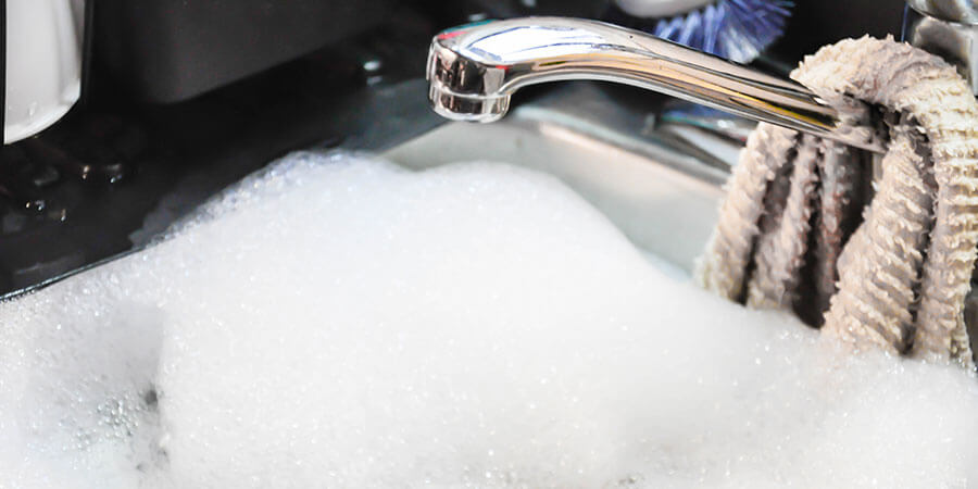 Restaurant sink filled with air fryer soaking solution and water