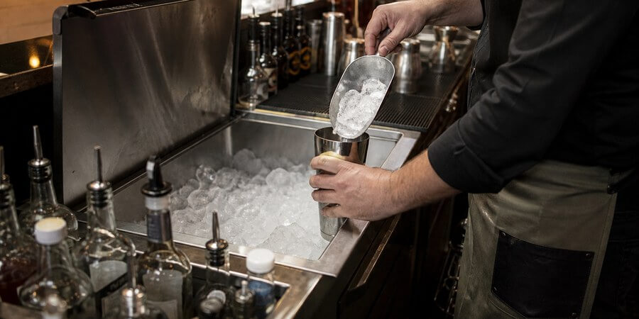 Bartender scooping ice from an underbar ice bin