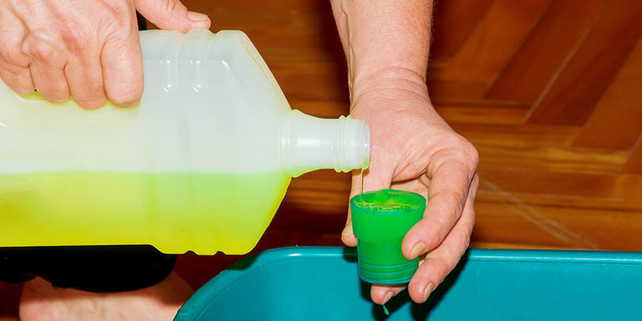 Gallon of cleaning solution being poured into capful for air fryer soaking