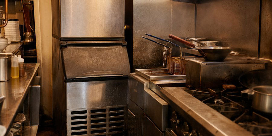 Commercial ice machine installed next to a restaurant fryer and range