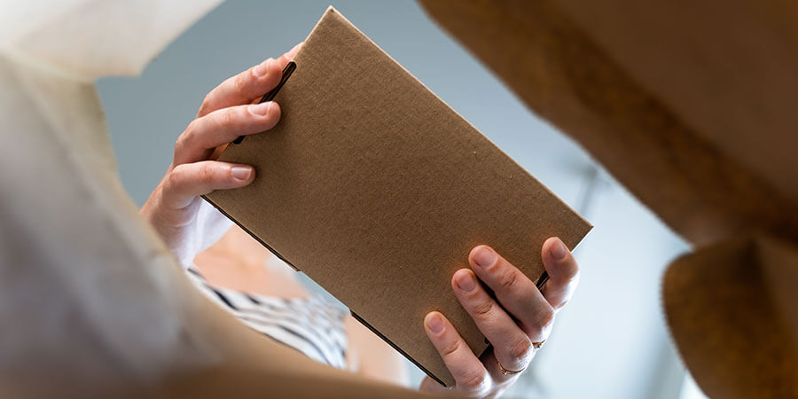 Woman placing cardboard box in a paper bag for takeout